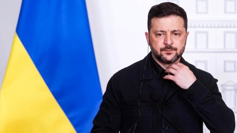 Zelensky standing on the background of a Ukraine flag